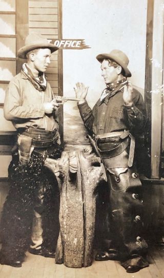 RPPC Studio portrait of cowboy holding up cowboy in front of Post Office 2