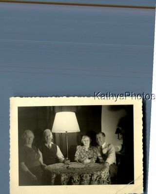 Found B&w Photo C,  7451 Men And Women Sitting At Table By Lamp