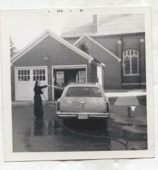 1969 Snapshot Of A Nun In Her Habit Hosing Down An Automobile In Front Of Church