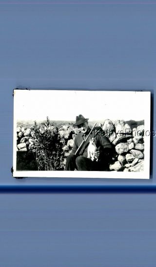 Found Vintage Photo D_6685 Man In Hat Sitting By Wall Holding Small Dog,  Rifle