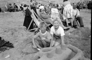 Old Negative.  Two Young Boys On Crowded Beach Making Sandcastles