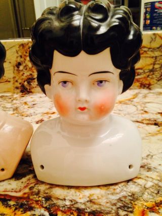 TWO DOLL HEADS,  INCLUDING ANTIQUE PORCELAIN DOLL HEAD Embossed 