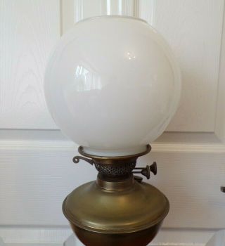 A Victorian brass oil lamp on a black glazed base with White shade order 3