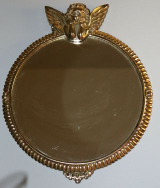 A Gazing Cherub With Wings On Top Of Round Brass Mirror