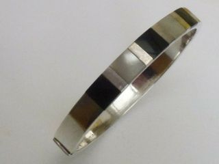 A VINTAGE HALLMARKED STERLING SILVER MOTHER OF PEARL & ONYX BANGLE 17.  8gms. 3