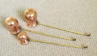 A SET OF THREE VINTAGE COPPER MEASURING CUPS / WARMING LADLES c/w BRASS HANDLES 3