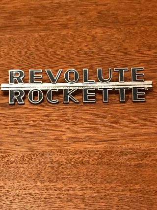 Vintage Revolute Rockette Metal Car Badge Charles Bruning Co.